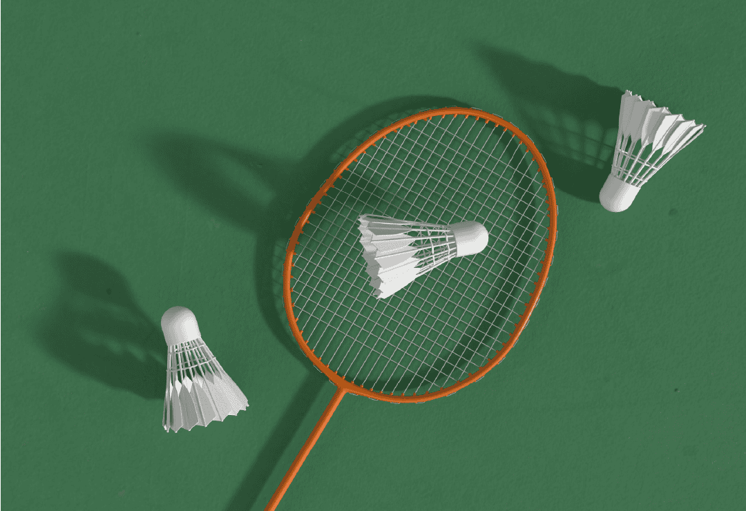 Badminton racket and shuttlecocks on green court surface.