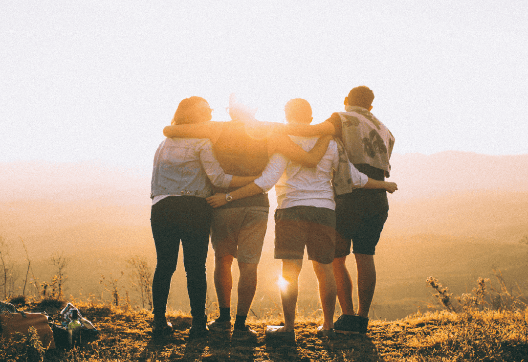 Group of friends embracing outdoors at sunset, symbolizing hope and community.