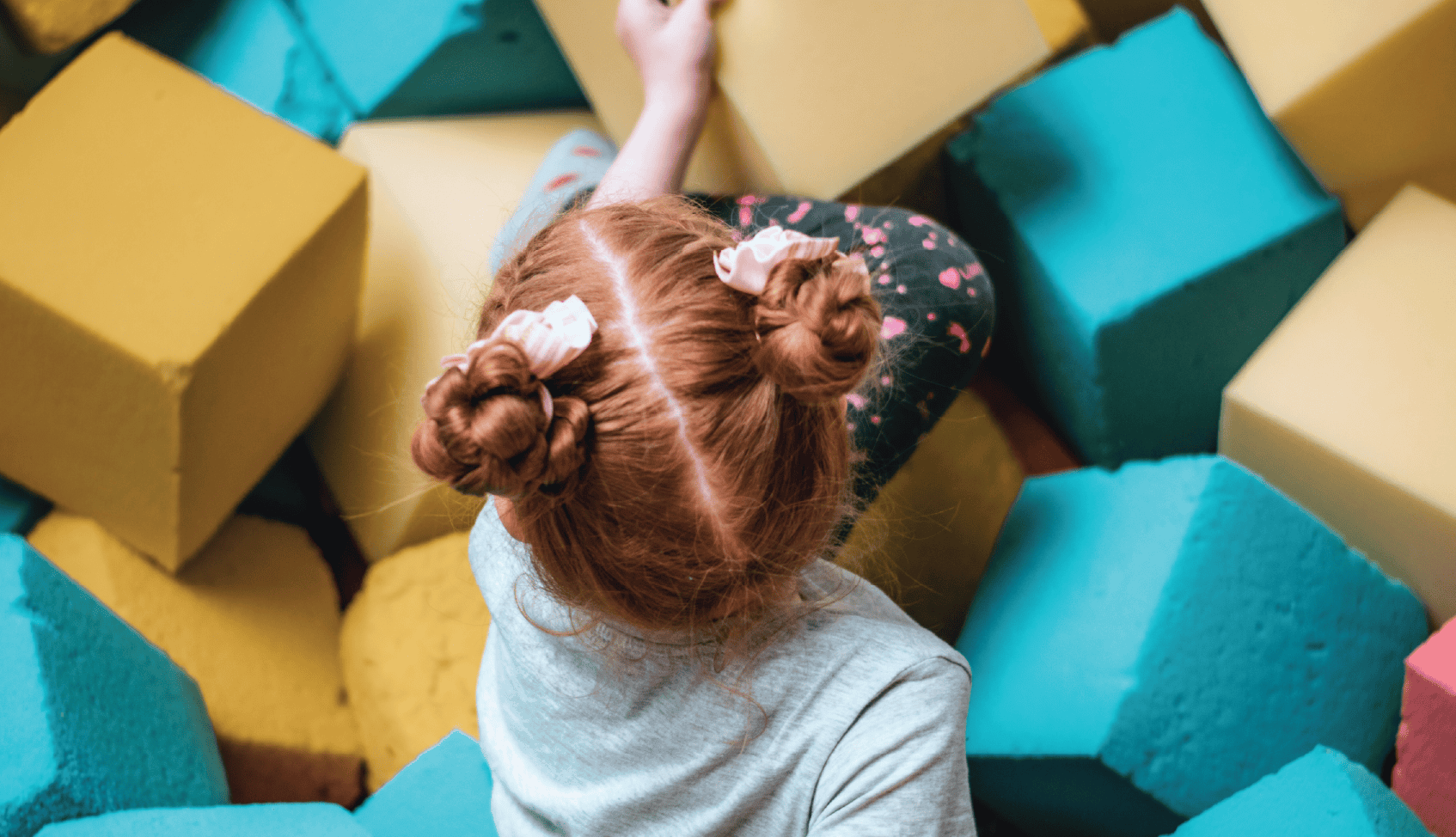 Child playing in colorful foam blocks at Tots +Co event.
