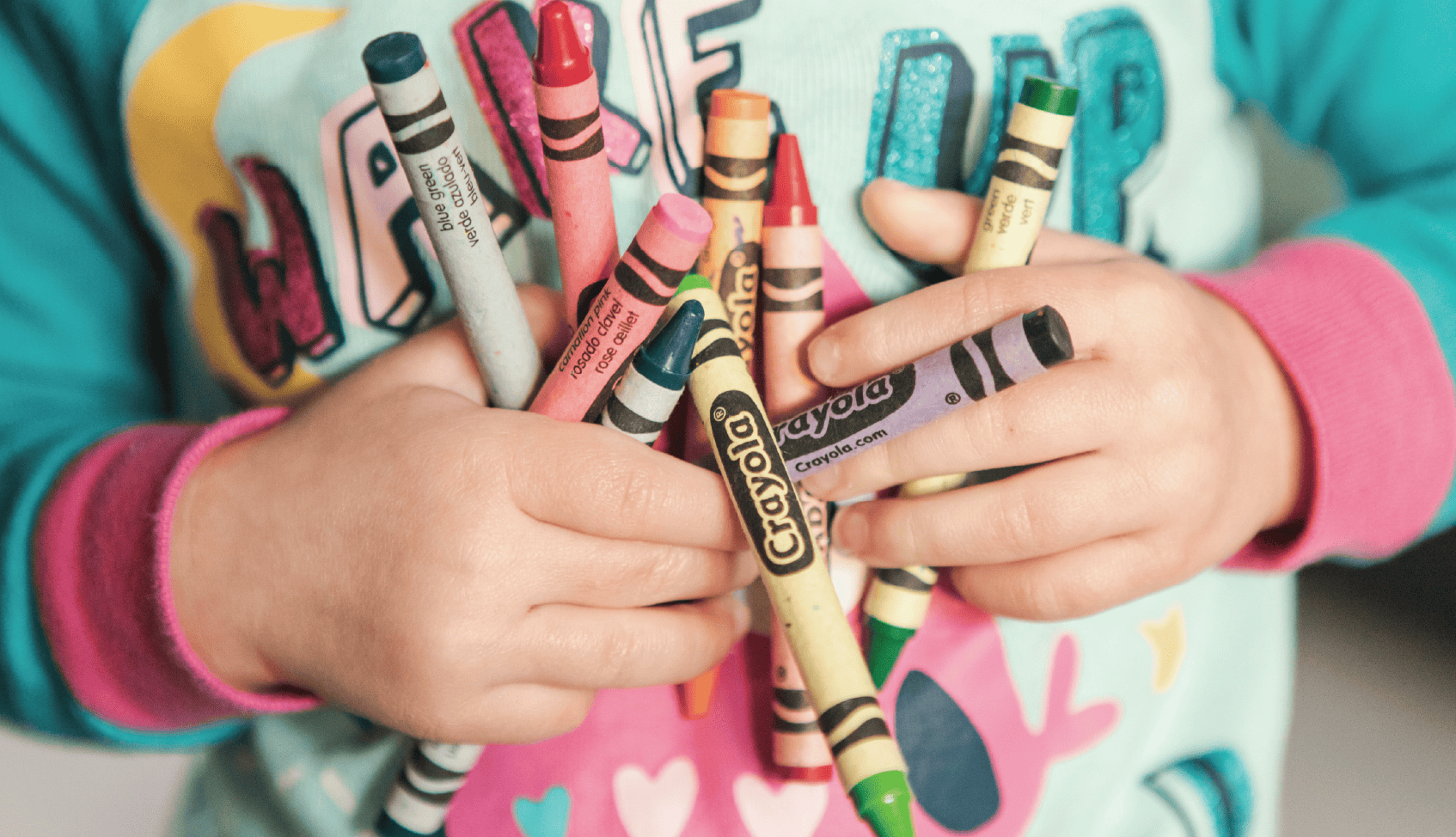 Children holding colorful crayons at Tots +Co event.